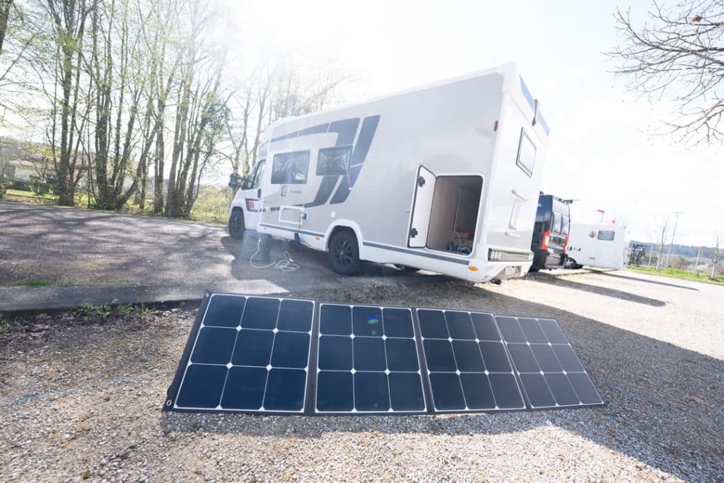 Panneaux solaires rechargeant une Bluetti Elite 400 à côté d’un camping-car