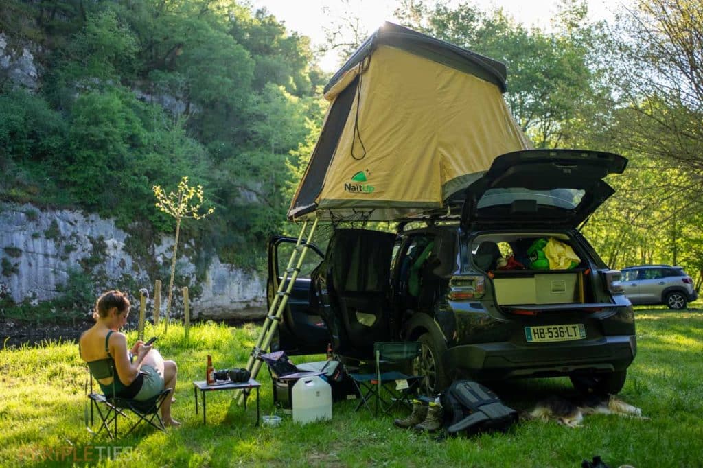 Voiture aménagée avec tente de toit installée en pleine nature dans la vallée du Célé dans le Lot