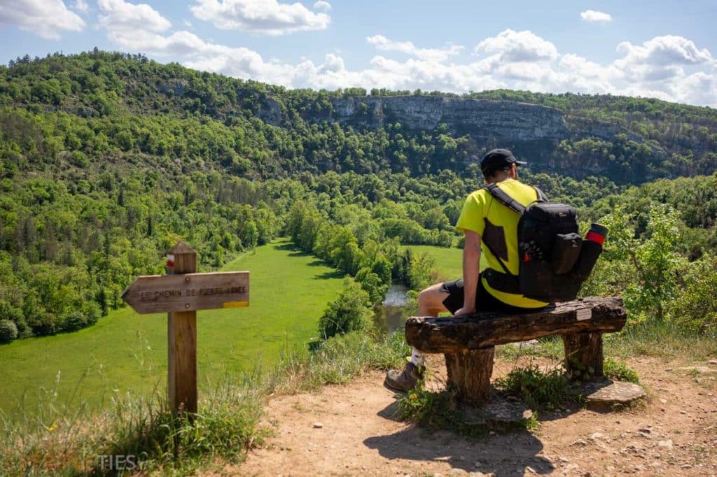 Randonneur assis face à la vallée du Célé lors d’une randonnée à Sauliac-sur-Célé