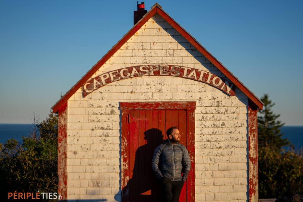 : Homme devant un bâtiment historique au cap Gaspé dans le parc national de Forillon
