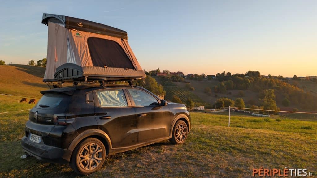 Voiture avec tente de toit dans les vignes au coucher du soleil dans l'est de la Slovénie